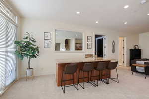 Indoor bar with light carpet, recessed lighting, and baseboards