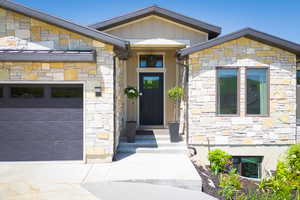 Doorway to property with stone siding, board and batten siding, and a garage