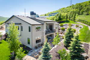 Rear view of house with a balcony, a patio, and roof with shingles