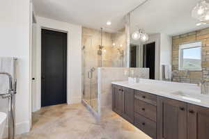 Full bath featuring a shower stall, double vanity, and baseboards