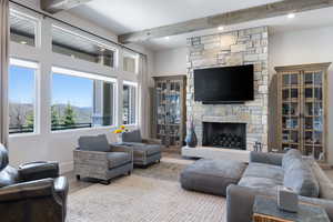 Living room with beam ceiling, wood finished floors, healthy amount of natural light, a fireplace, and recessed lighting