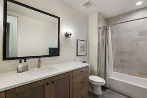 Full bathroom featuring toilet, vanity, shower / tub combo with curtain, and recessed lighting