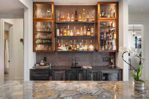 Indoor wet bar featuring tasteful backsplash and beverage cooler