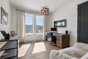 Office area with a chandelier, light wood-style flooring, and baseboards