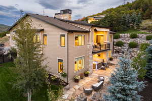 Rear view of house with a patio area, a balcony, and a shingled roof