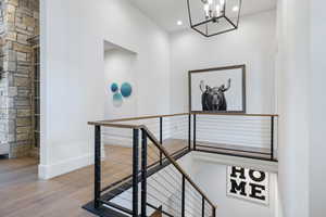 Stairway with wood finished floors, baseboards, a chandelier, and recessed lighting