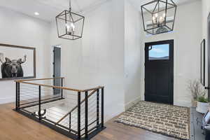 Entrance foyer featuring a chandelier, a high ceiling, baseboards, wood-type flooring, and recessed lighting