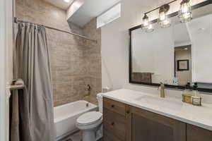 Full bathroom with vanity, shower / bath combination with curtain, and toilet