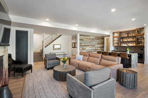 Living room featuring bar, stairs, recessed lighting, light wood-type flooring, and a fireplace