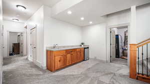 Bar featuring light colored carpet, a sink, baseboards, recessed lighting, and stairs