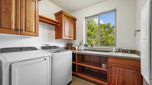 Laundry area with cabinet space, washer and clothes dryer, healthy amount of natural light, and dark tile patterned floors
