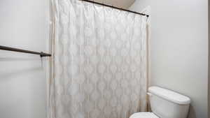 Bathroom featuring toilet and curtained shower