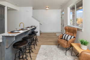 Kitchen with light wood-type flooring, a breakfast bar area, a sink, and baseboards