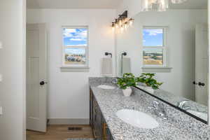 Bathroom featuring a chandelier, wood finished floors, baseboards, and double vanity