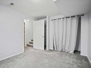 Unfurnished bedroom featuring carpet flooring, baseboards, and a textured ceiling