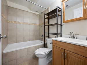Full bath featuring toilet, vanity, tiled shower / bath, and tile patterned floors