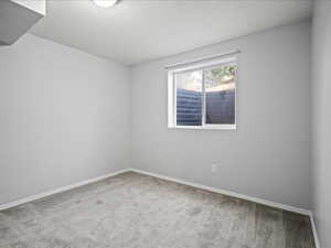 Carpeted empty room featuring baseboards and a textured ceiling