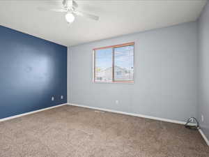 Empty room featuring carpet, baseboards, and a ceiling fan