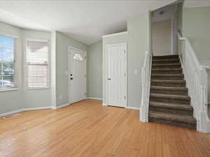 Foyer with light wood-style floors, stairs, and baseboards