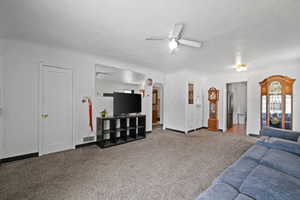 Living room with ceiling fan, carpet, baseboards, and arched walkways