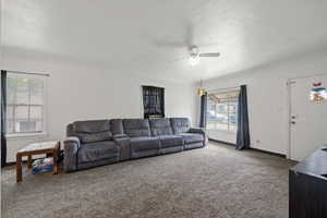Living area with carpet floors, a ceiling fan, and baseboards