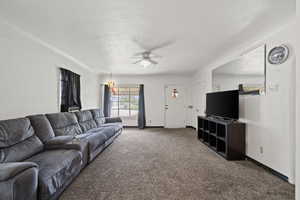 Carpeted living area featuring a ceiling fan and baseboards