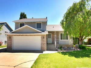 Tri-level home featuring brick siding, a porch, a front lawn, concrete driveway, and a garage