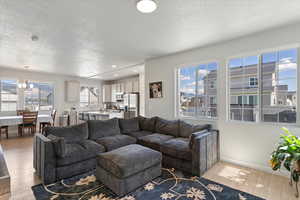 Living area with a textured ceiling, light wood-style flooring, recessed lighting, a chandelier, and baseboards