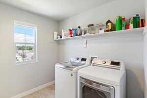 Laundry room featuring separate washer and dryer, baseboards, and a textured ceiling