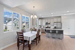Dining area featuring light wood-style floors, a chandelier, baseboards, recessed lighting, and a textured ceiling
