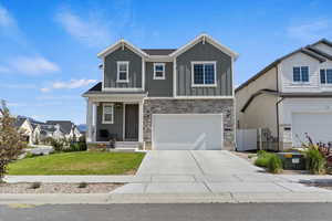 View of front of house with board and batten siding, a garage, stone siding, and driveway