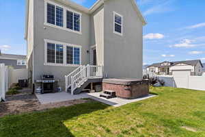 Rear view of property with a hot tub, a patio, stucco siding, and central AC