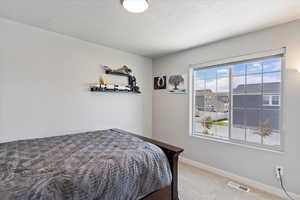 Carpeted bedroom featuring a textured ceiling and baseboards