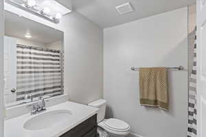Full bath featuring toilet, a shower with curtain, and vanity