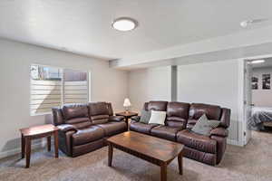 Living area with light carpet, a textured ceiling, and baseboards