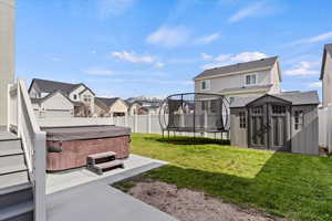 View of yard featuring a hot tub, a trampoline, a residential view, and a patio