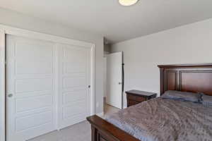 Bedroom with light colored carpet and a closet