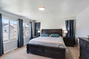 Bedroom featuring light carpet, baseboards, and a textured ceiling