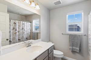 Full bath featuring toilet, vanity, and curtained shower