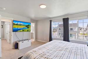 Carpeted bedroom featuring a textured ceiling and baseboards