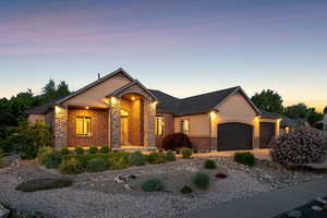 View of front of property with an attached garage, stucco siding, stone siding, driveway, and brick siding