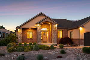 Traditional-style home with brick siding, an attached garage, roof with shingles, driveway, and stucco siding