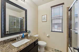 Full bathroom with an enclosed shower, toilet, and vanity