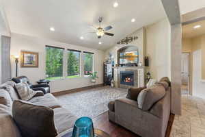 Living room with a ceiling fan, a high end fireplace, recessed lighting, and vaulted ceiling