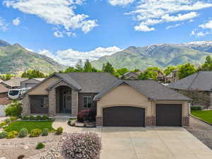 View of front of home with an attached garage, brick siding, concrete driveway, a mountain view, and stucco siding