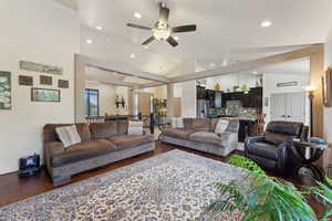 Living room featuring vaulted ceiling, a ceiling fan, dark wood finished floors, and recessed lighting
