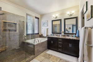 Full bathroom with a garden tub, a shower stall, double vanity, and stone tile flooring