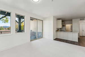 Unfurnished living room featuring dark carpet and baseboards