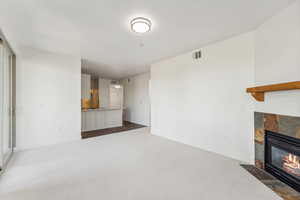 Unfurnished living room featuring dark colored carpet, a tile fireplace, and baseboards