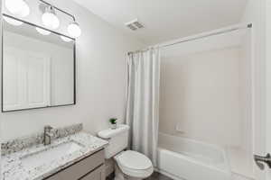 Bathroom featuring vanity, toilet, and shower / bathtub combination with curtain